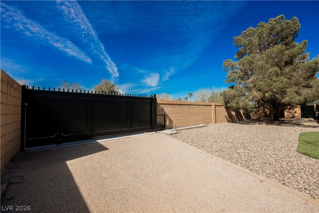 601 Sandy Drive, Henderson, NV 89002 Secure gated access opens to a wide gravel driveway bordered by solid block fencing.