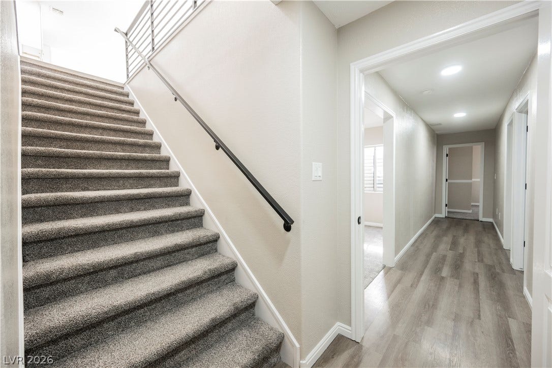 601 Sandy Drive, Henderson, NV 89002 Carpeted stairs ascend next to a wood-look plank hallway with recessed lighting.