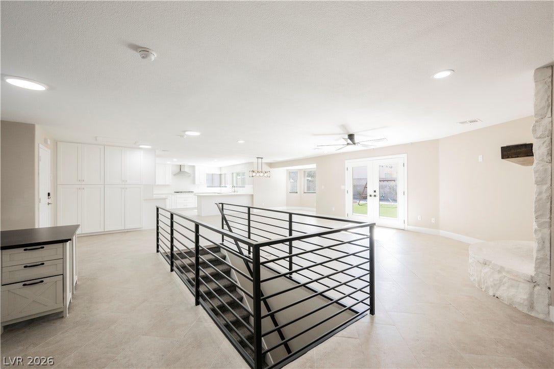 601 Sandy Drive, Henderson, NV 89002 An open floorplan connects the living area, kitchen, and a central staircase with metal railings.