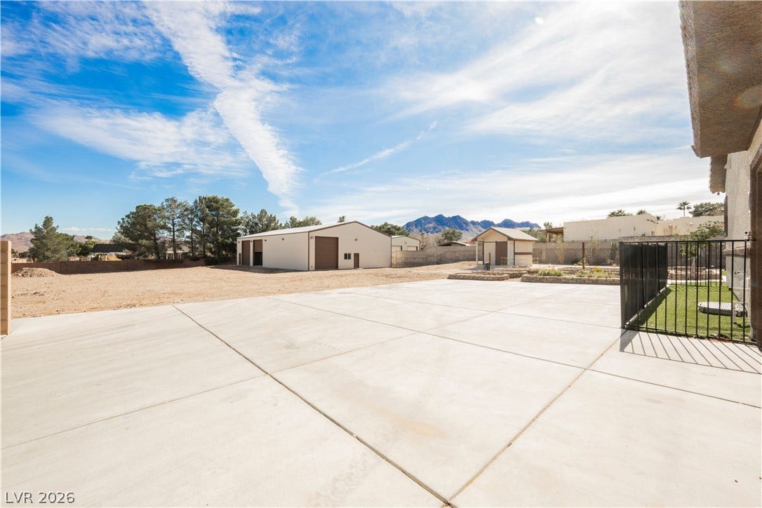 601 Sandy Drive, Henderson, NV 89002 An expansive concrete patio overlooks a spacious yard with outbuildings and distant mountain views.
