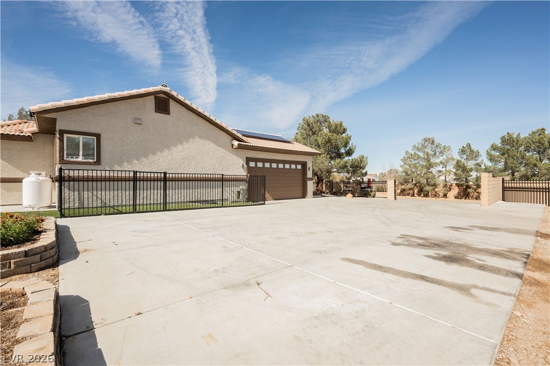 601 Sandy Drive, Henderson, NV 89002 An expansive concrete driveway leads to a stucco exterior with a tiled roofline.