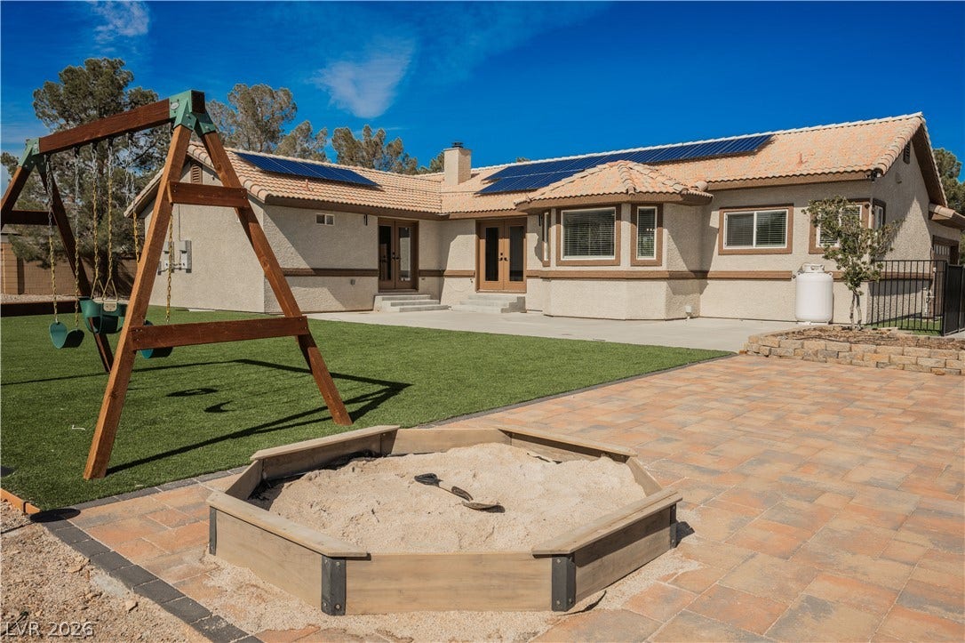 601 Sandy Drive, Henderson, NV 89002 A spacious backyard patio area sits alongside manicured lawn and classic stucco architecture.