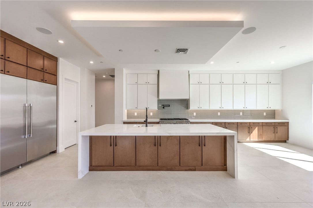 3051 E Serene Avenue, Henderson, NV 89074 A spacious kitchen features wood cabinetry, stone countertops, and an integrated ceiling architectural detail.