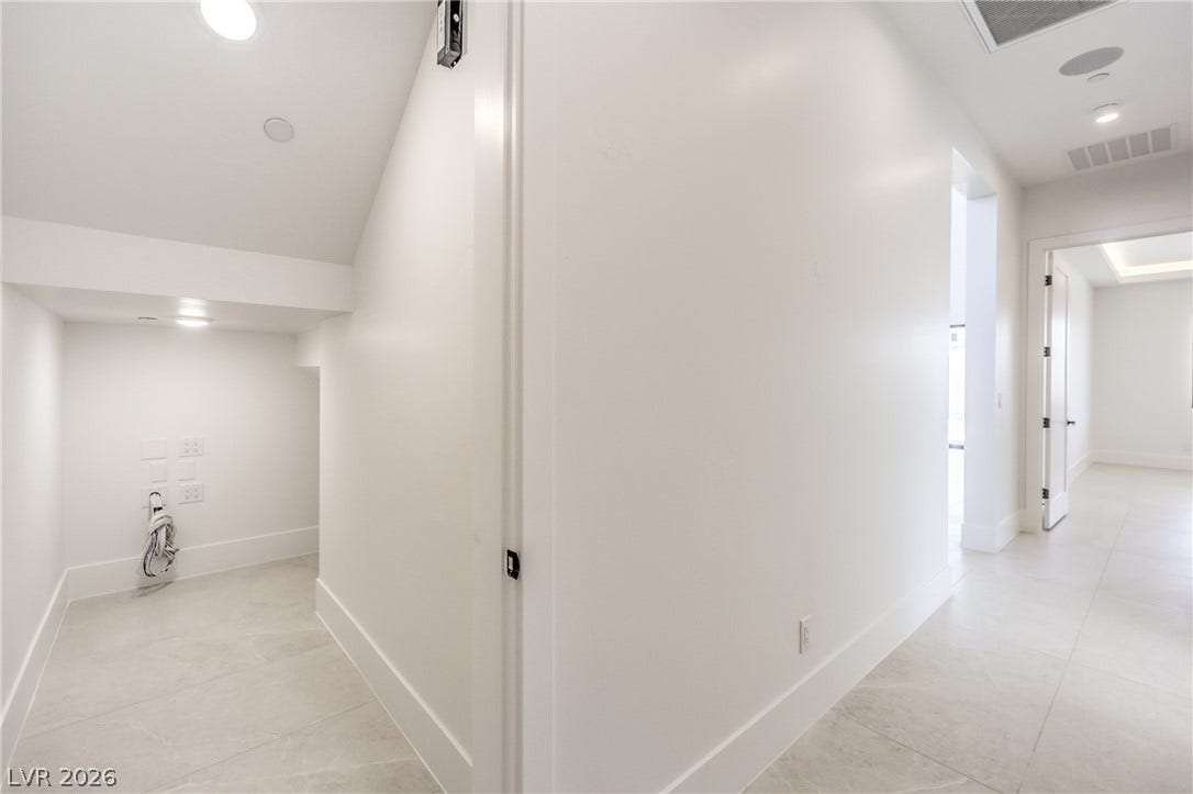 3051 E Serene Avenue, Henderson, NV 89074 Crisp white walls and stone tile flooring define this modern hallway layout.