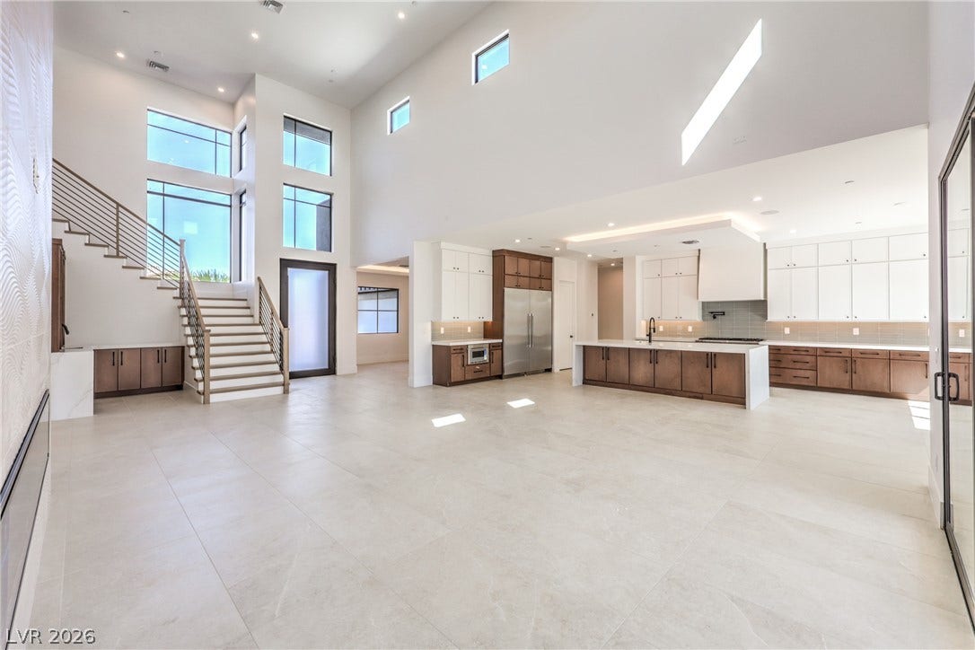 3051 E Serene Avenue, Henderson, NV 89074 Double-height ceilings and tall windows anchor this expansive open-concept living space and kitchen.