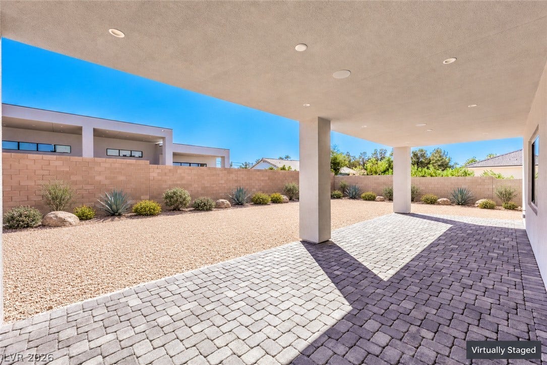 3051 E Serene Avenue, Henderson, NV 89074 A spacious covered patio features elegant paver flooring and recessed lighting overlooking the gravel yard.