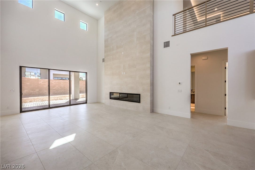 3051 E Serene Avenue, Henderson, NV 89074 Towering ceilings and a massive floor-to-ceiling fireplace anchor this light-filled modern living room.