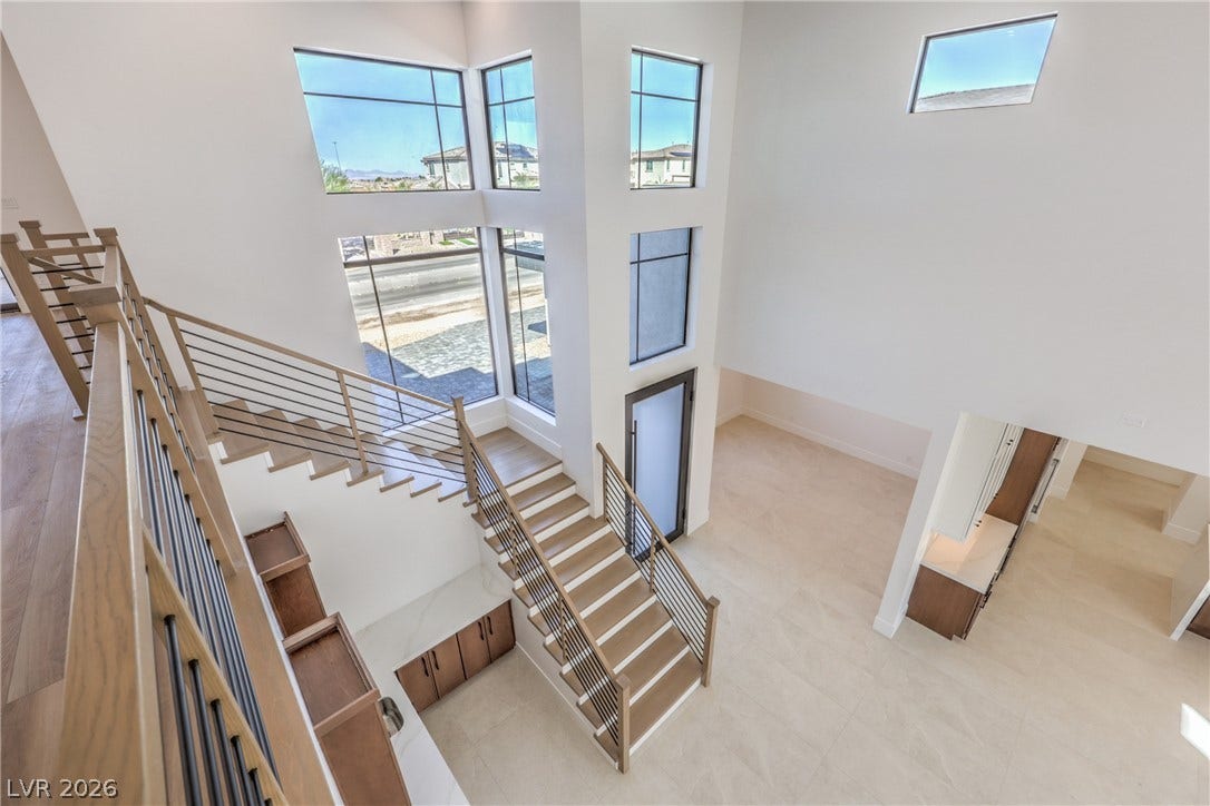 3051 E Serene Avenue, Henderson, NV 89074 Towering ceilings and multi-level windows illuminate the sculptural modern staircase and open lower-level layout.