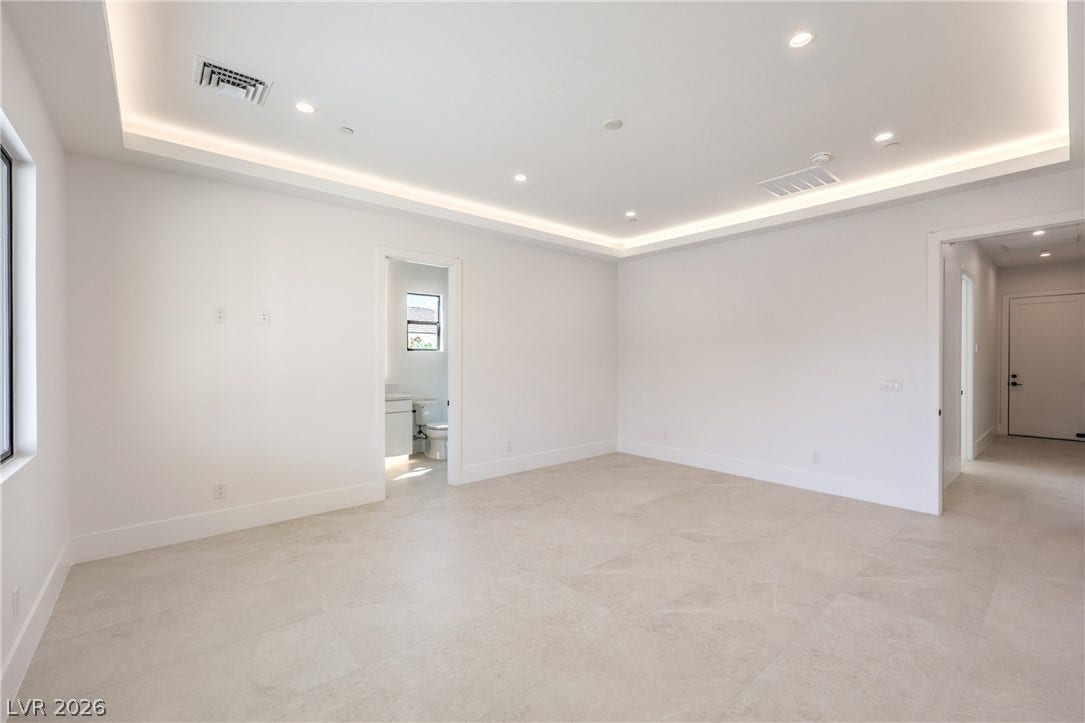 3051 E Serene Avenue, Henderson, NV 89074 Recessed lighting and a detailed tray ceiling elevate this open, tile-floored living space.