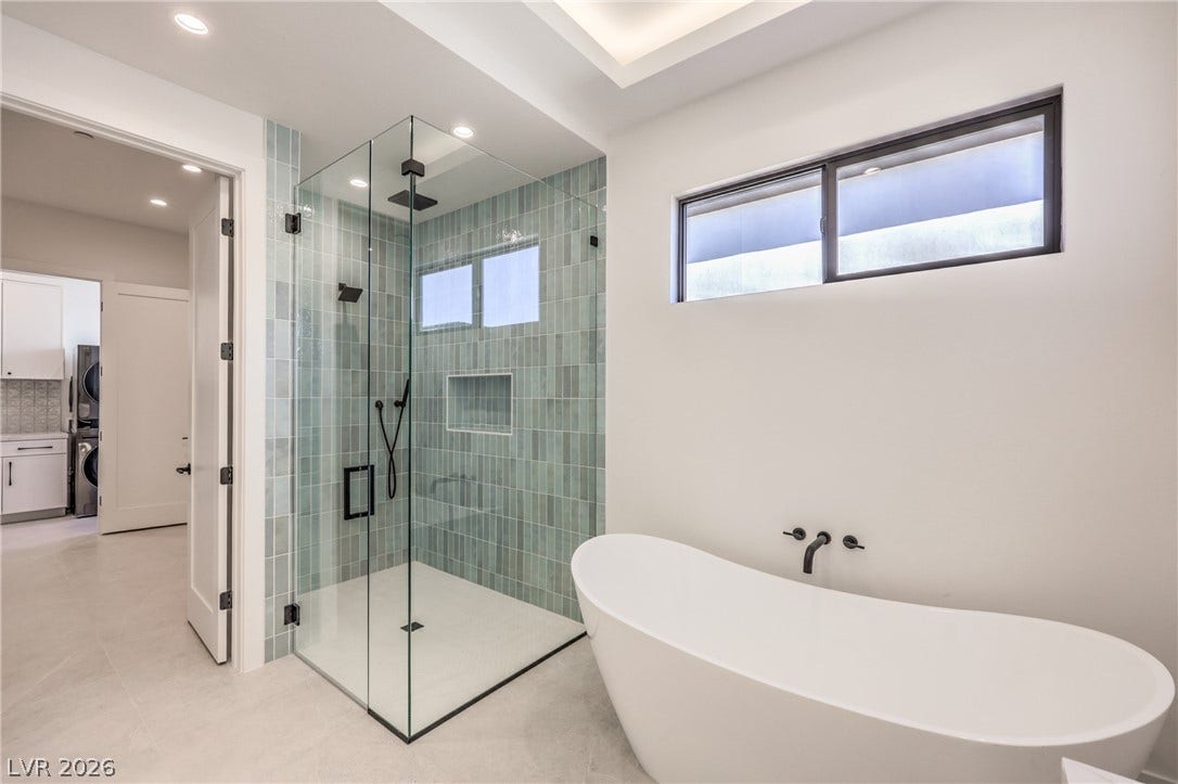 3051 E Serene Avenue, Henderson, NV 89074 A contemporary soaking tub sits adjacent to a glass-enclosed shower with vertical tile accents.