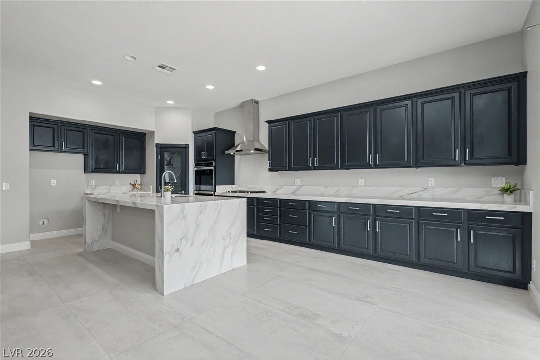 7126 Spindle Berry Street, Las Vegas, NV 89131 Clean lines and stone countertops define this spacious modern kitchen with dark cabinetry.