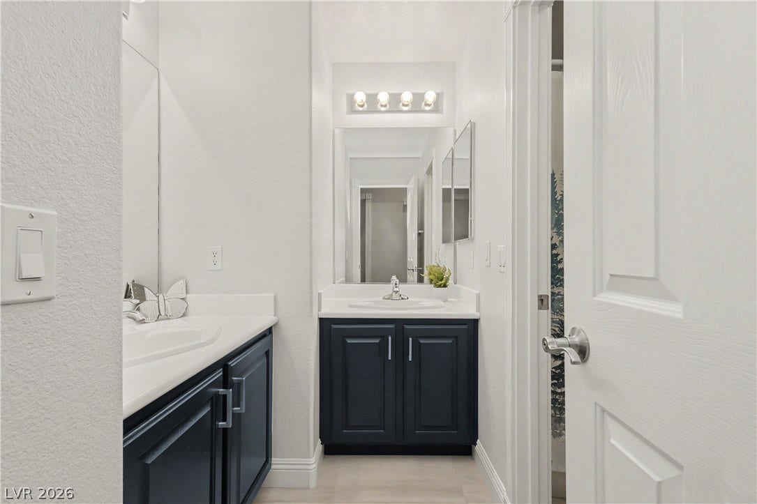 7126 Spindle Berry Street, Las Vegas, NV 89131 Contrasting dark cabinets define this sleek bathroom featuring multiple vanities and updated fixtures.
