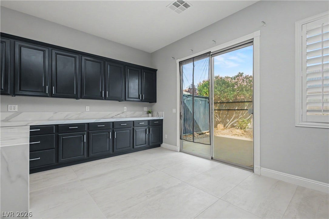 7126 Spindle Berry Street, Las Vegas, NV 89131 Sliding glass doors open from this versatile space with dark cabinetry to the backyard.