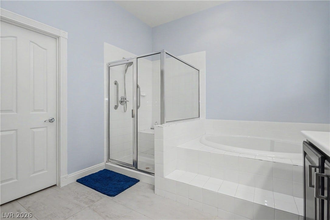7126 Spindle Berry Street, Las Vegas, NV 89131 Tiled stairs lead to a deep soaking tub alongside a separate glass-enclosed shower.