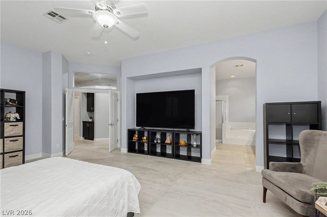 7126 Spindle Berry Street, Las Vegas, NV 89131 A spacious bedroom features neutral tile flooring, high ceilings, and an arched entry leading to the bath.