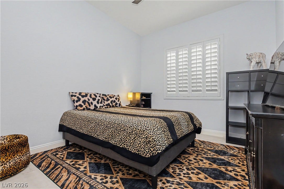 7126 Spindle Berry Street, Las Vegas, NV 89131 Crisp white walls and clean tile flooring frame a sunlit bedroom with custom plantation shutters.