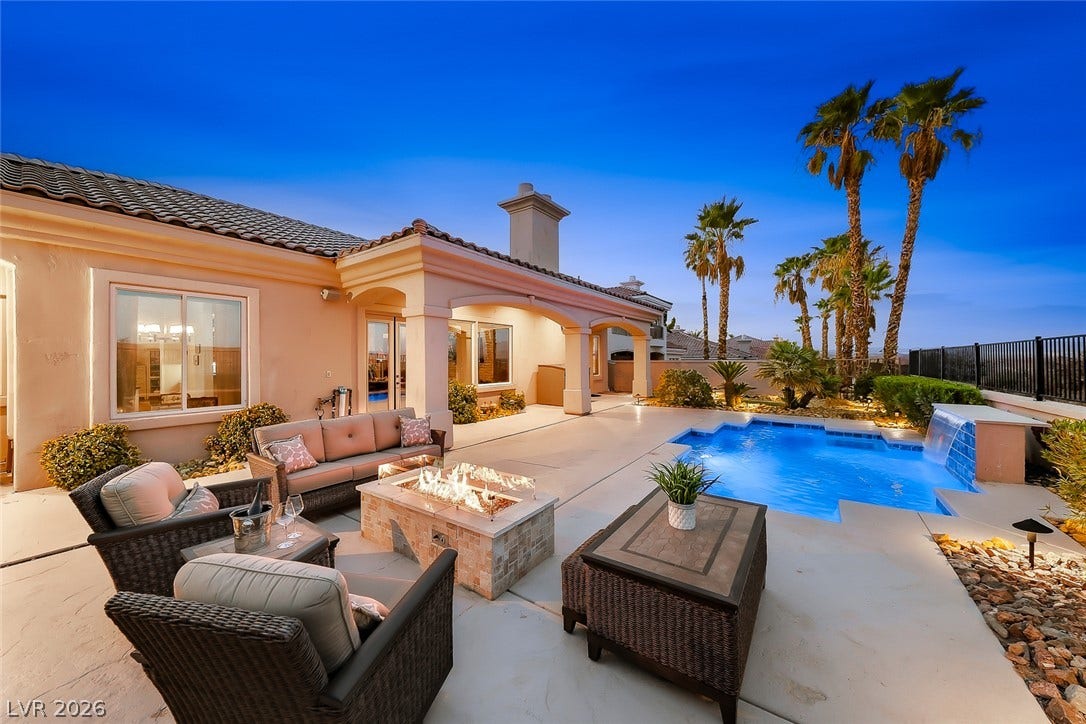 An inviting backyard oasis features a sparkling custom pool alongside a stone-paved patio.