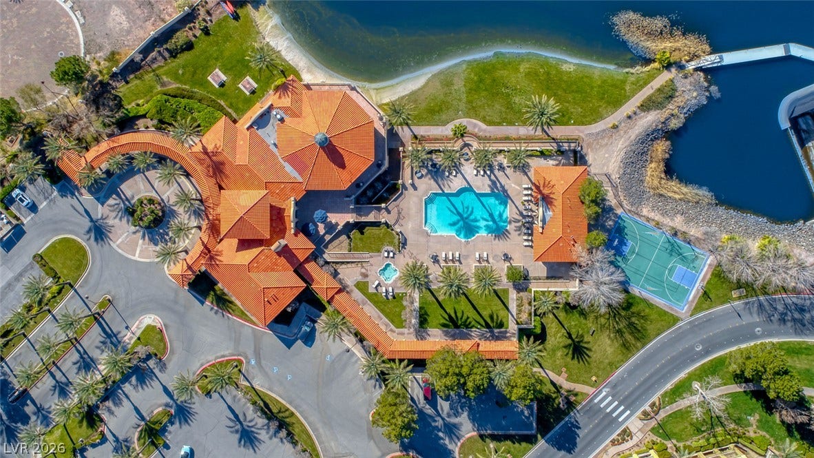 Aerial view reveals an expansive lakefront estate complete with private pool, spa, and sports court.