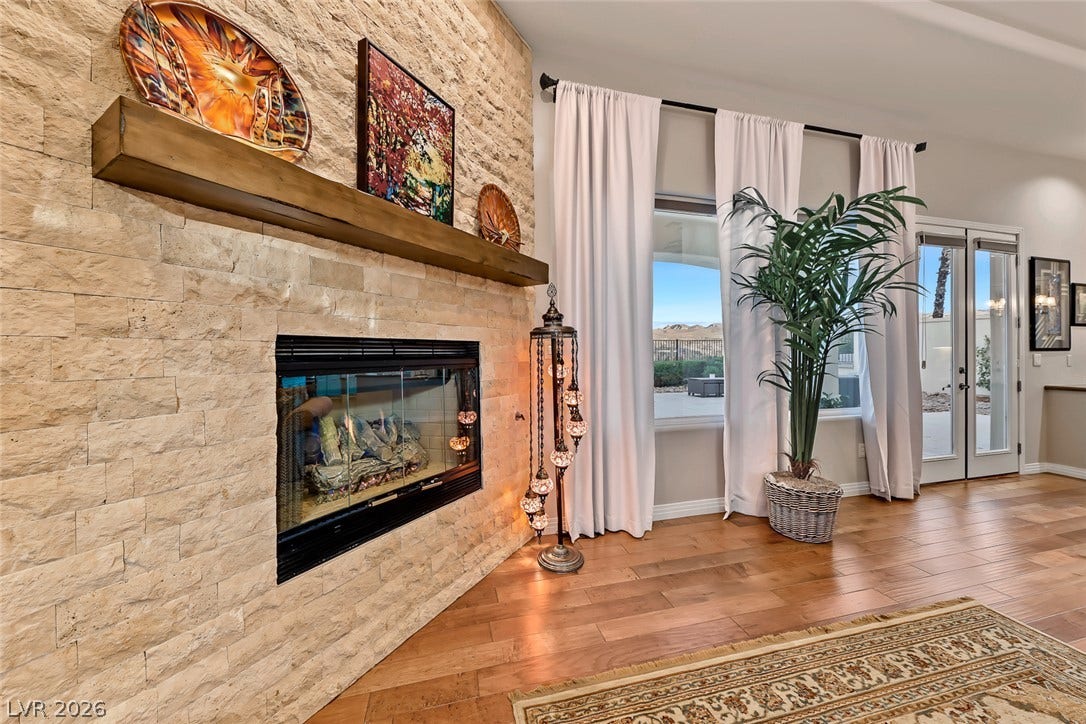 Rich hardwood floors complement a floor-to-ceiling stone fireplace in this inviting living space.