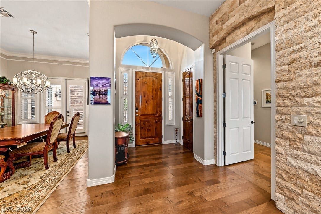 Rich hardwood floors and a stone accent wall frame this welcoming entryway.