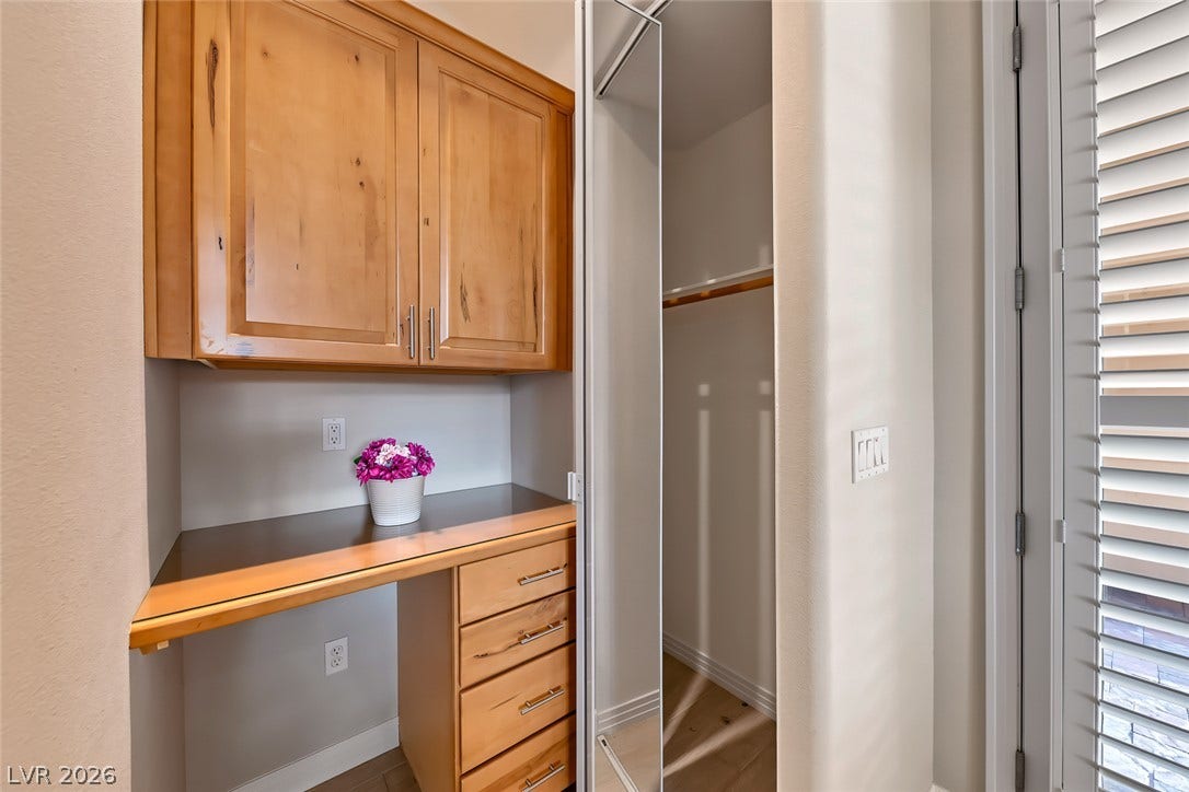 Rich wood cabinetry creates a functional workspace alongside a mirrored walk-in closet.