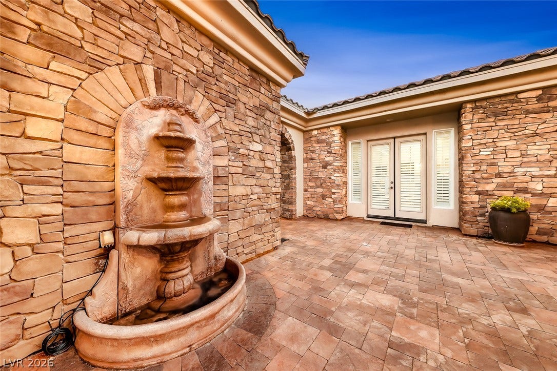 An inviting stone-clad courtyard features a tiered water fountain and paved patio tiles.