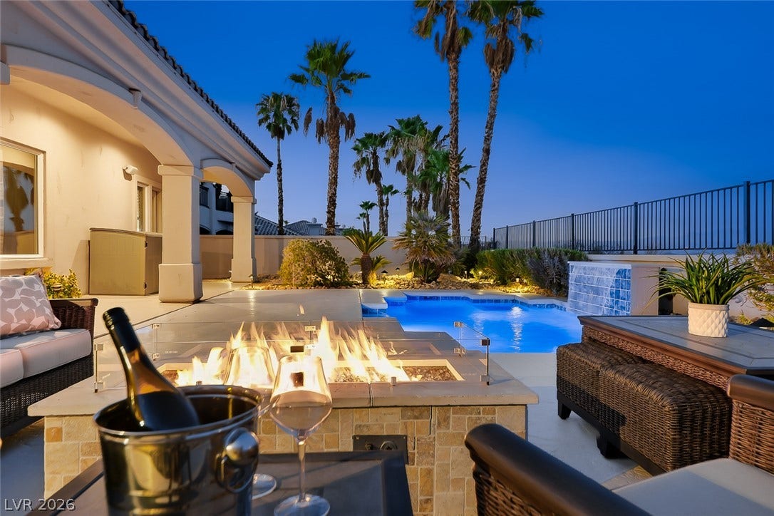An inviting backyard oasis showcases a stone-accented fire pit alongside a sparkling swimming pool.