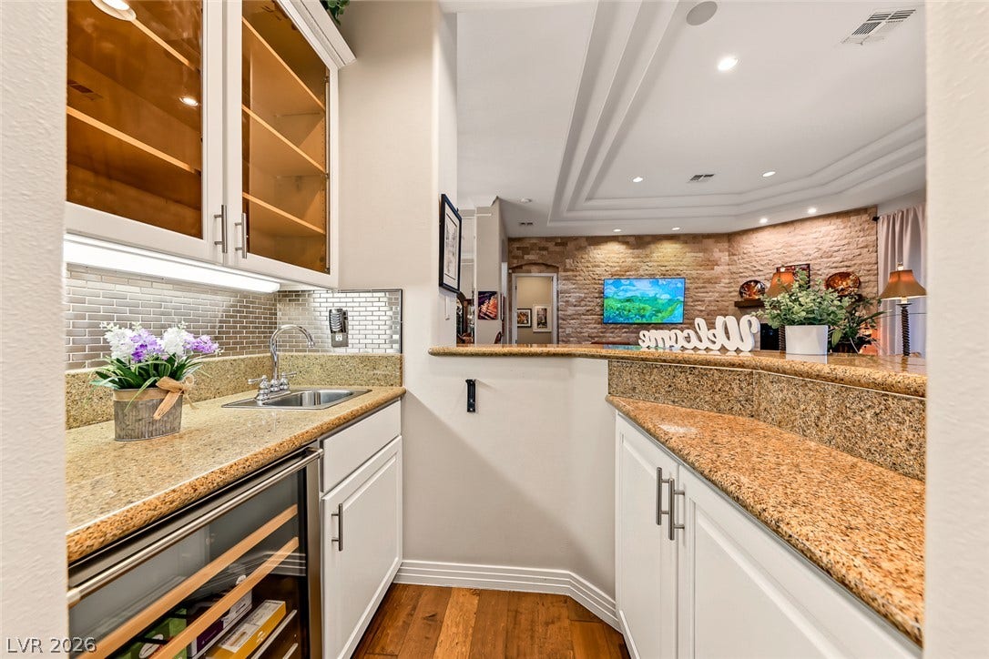 Rich wood floors and premium stone countertops define this elegant wet bar area.