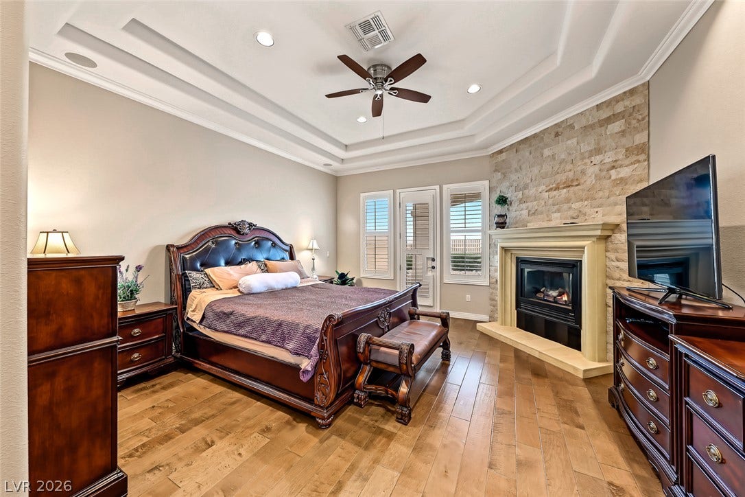 Gleaming hardwood floors and a stone fireplace anchor this cozy bedroom space.