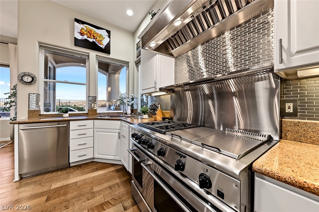 Professional culinary appliances and detailed tile backsplashes highlight this spacious kitchen workspace.