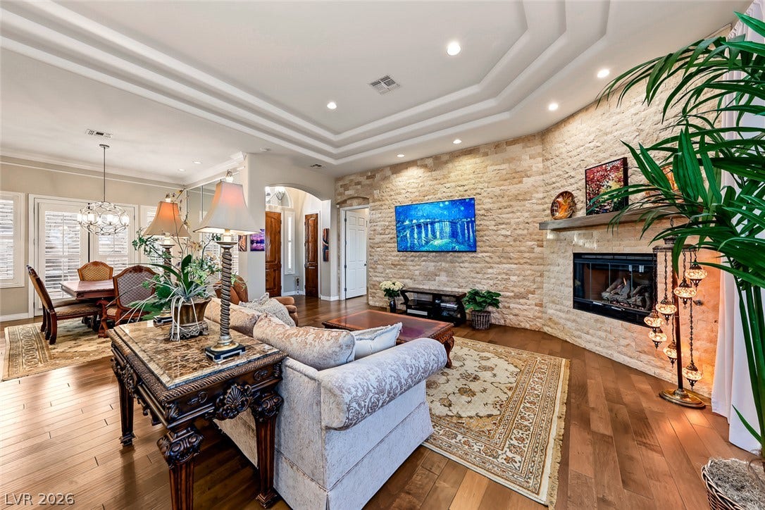 Warm hardwood flooring meets a stone accent wall framing the integrated fireplace.