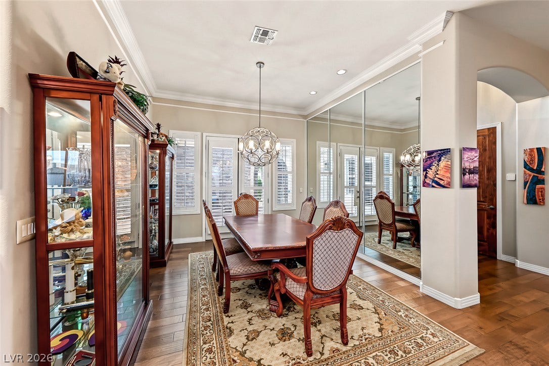 Elegant crown molding complements warm wood flooring in this formal dining area.