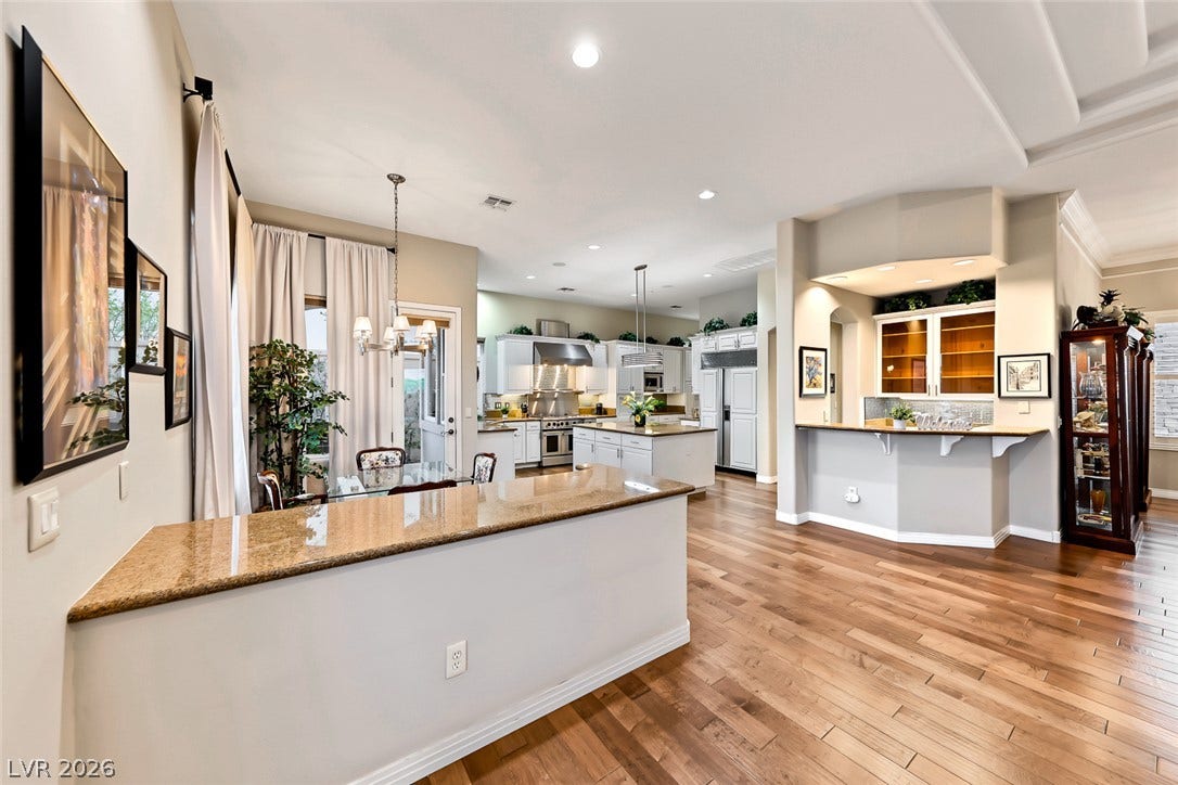 Rich hardwood flooring anchors the wide-open living, dining, and kitchen layout.