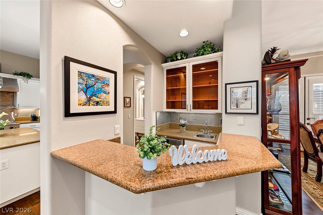 Polished granite countertops and custom glass-front cabinetry define this elegant built-in wet bar setup.