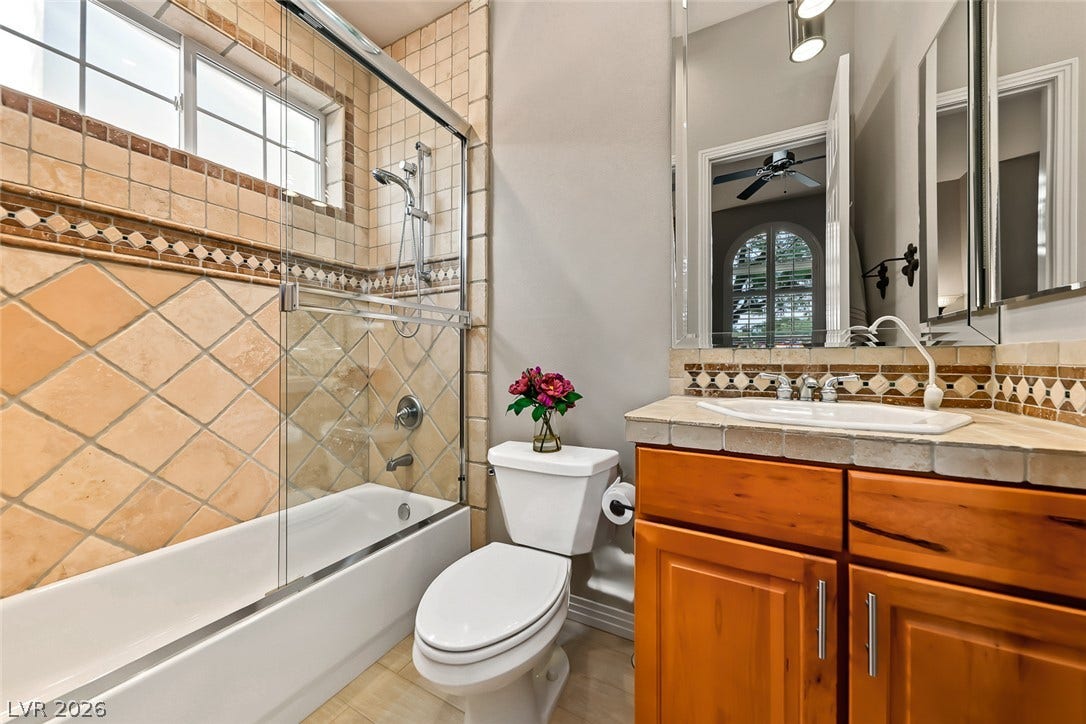 Tiled accents and warm wood cabinetry define this inviting full bathroom.