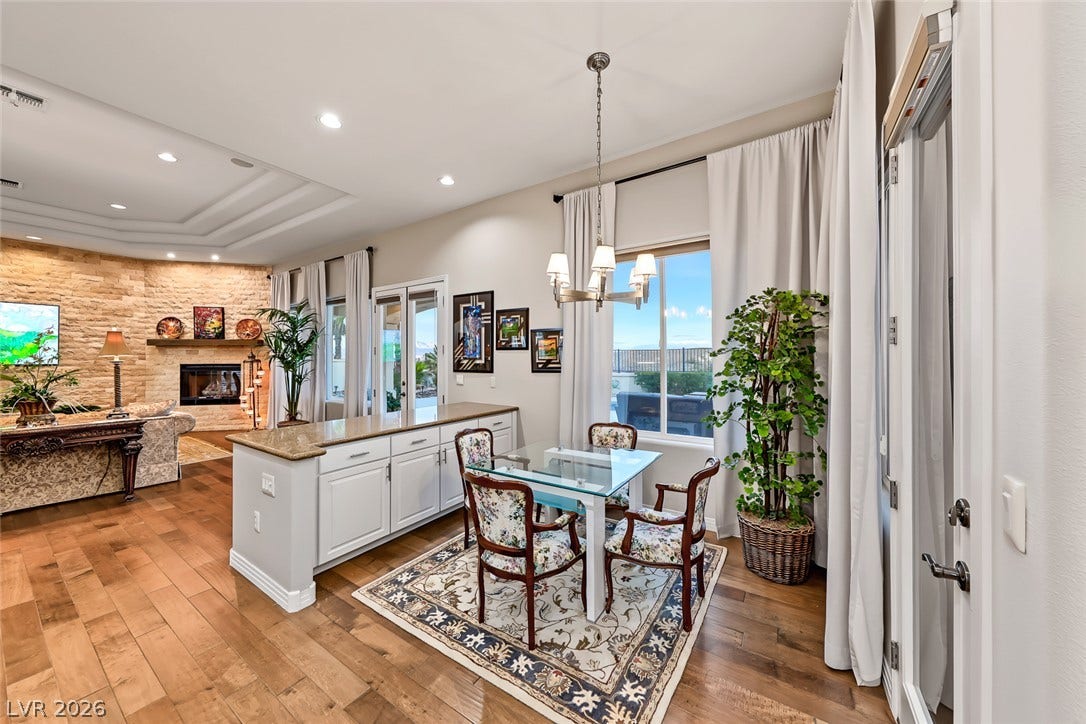 Rich wood floors and a stone fireplace wall anchor this inviting open-concept living area.