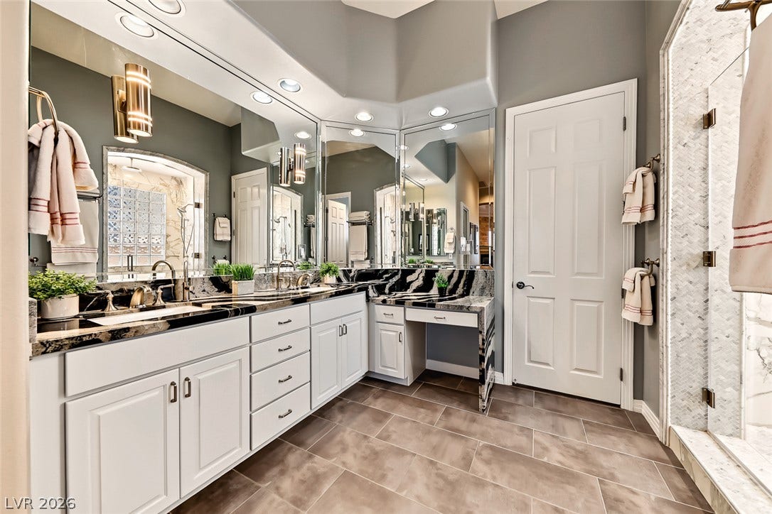 High ceilings and a stone-topped double vanity define this elegant primary bathroom.