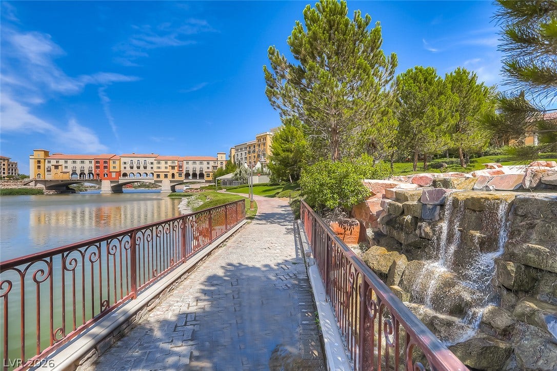 Lush landscaping and a stone waterfall frame the scenic lakeside walking paths.