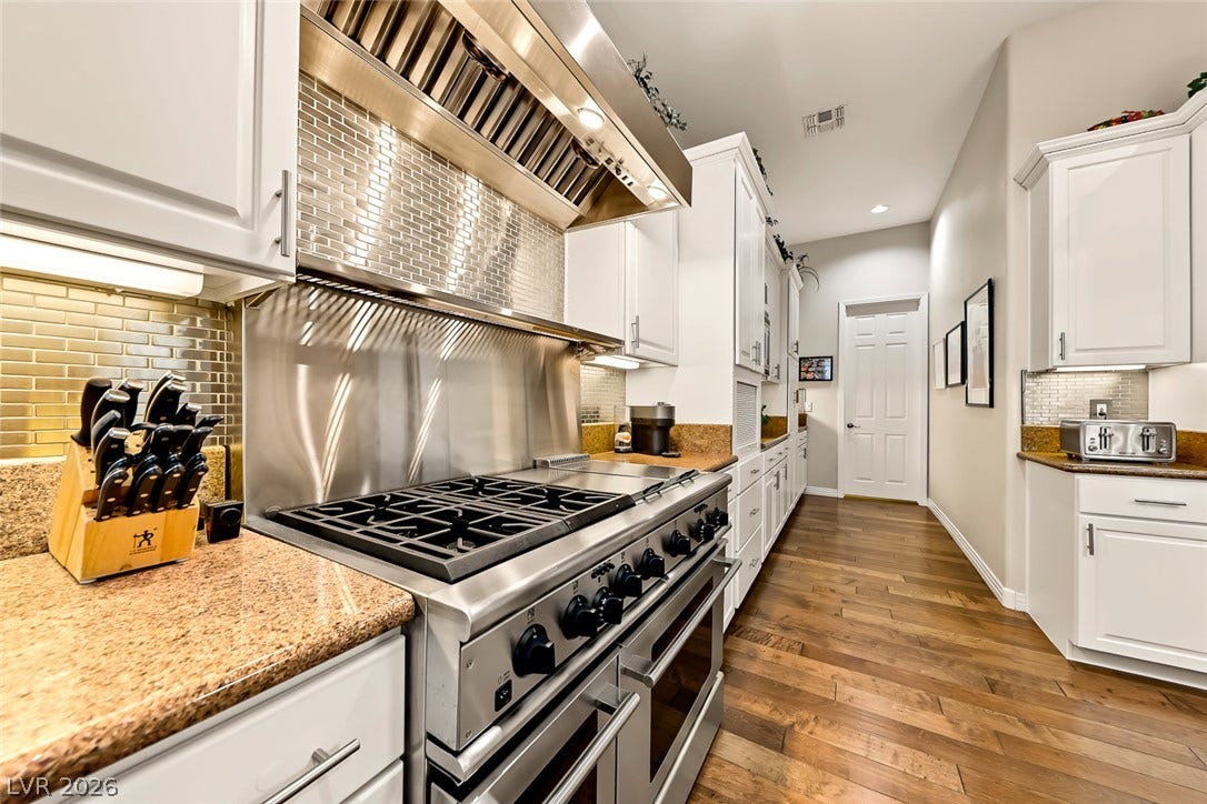 Polished stone countertops complement the professional-grade range and warm hardwood floors in this galley kitchen.