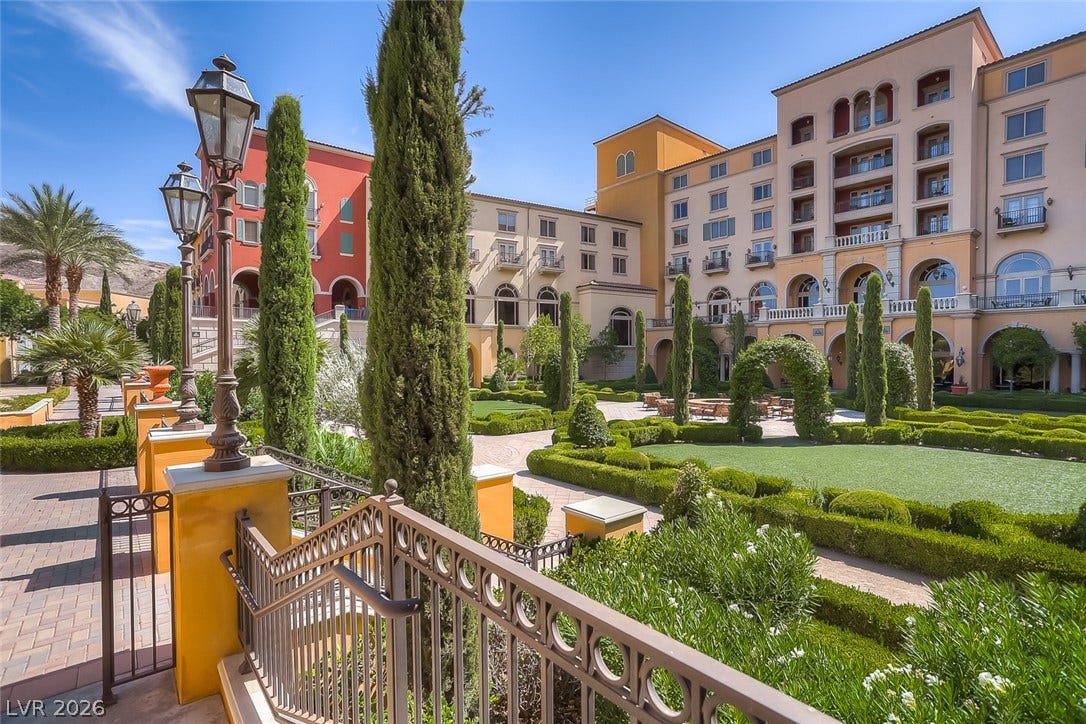 Manicured hedges and towering cypress trees frame a Mediterranean-inspired courtyard garden.