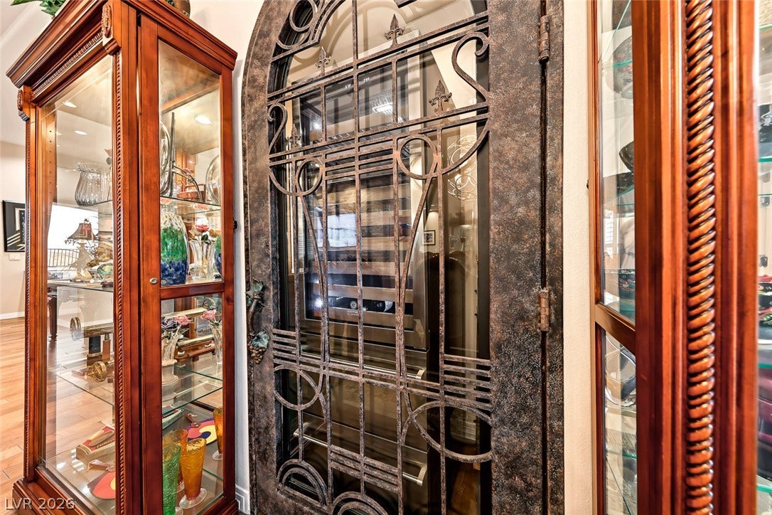 An arched wrought-iron gate secures the custom built-in wine storage.