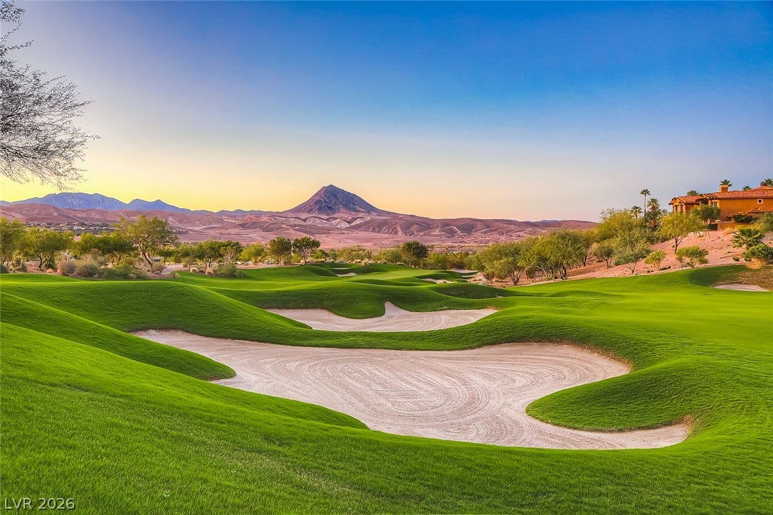 Lush fairways yield to dramatic mountain peaks under a clear desert sky.