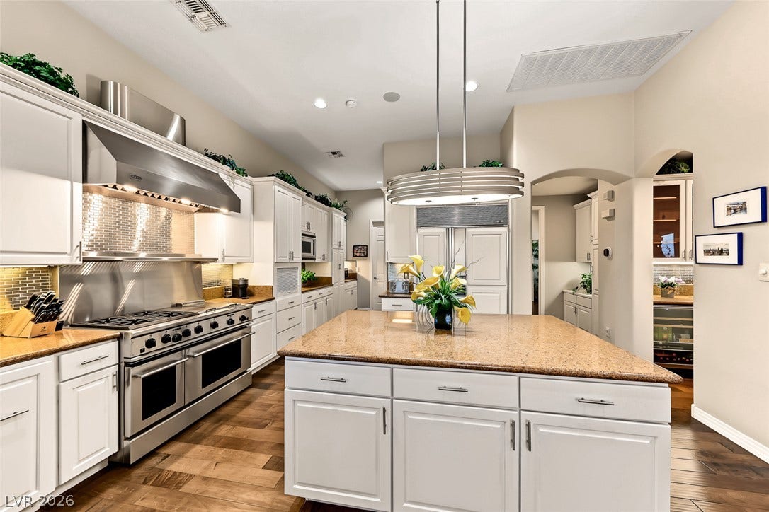 A spacious kitchen features warm hardwood floors, granite countertops, and premium built-in appliances.