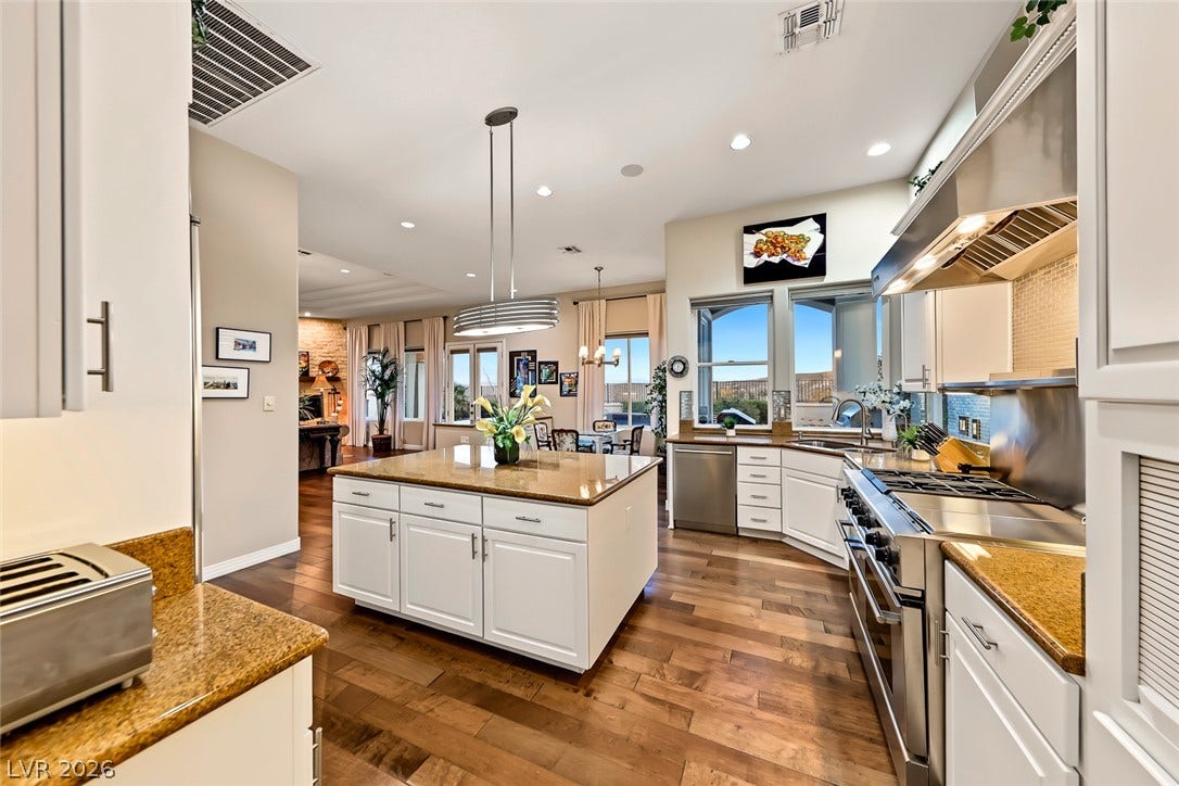 Rich hardwood floors anchor this kitchen workspace complete with a center island and stone counters.