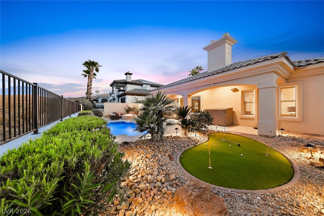 An inviting backyard oasis showcases a private putting green alongside a sparkling swimming pool.