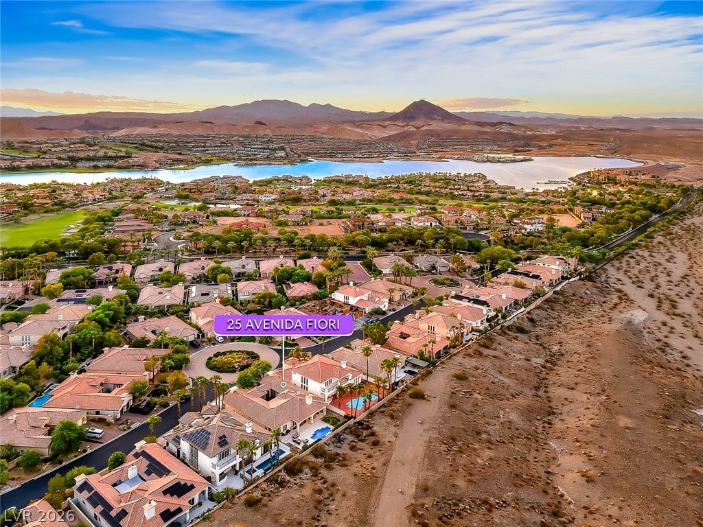 A striking neighborhood borders a vast blue lake framed by distant desert mountains.