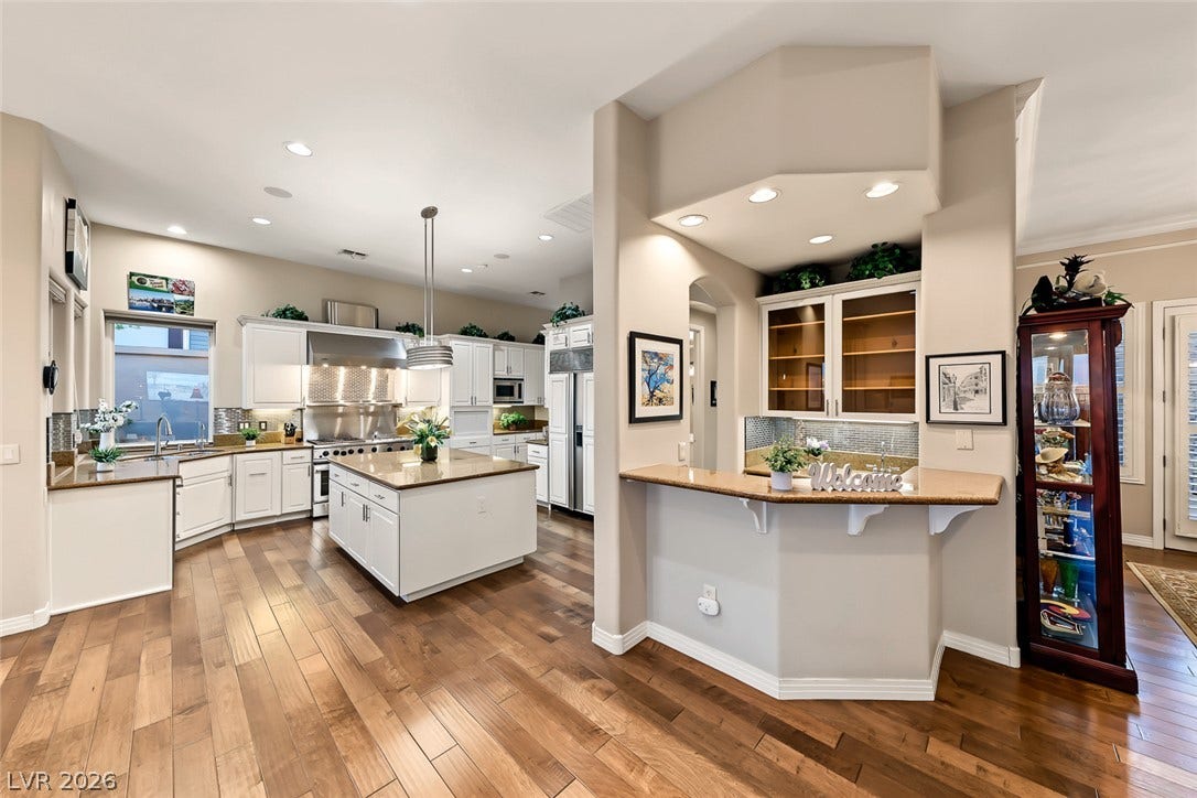 Rich hardwood flooring anchors the expansive, open culinary space featuring built-in cabinetry and dual counter areas.