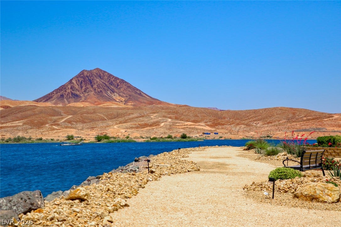 A gravel pathway traces the shoreline, offering clear views of the water and desert mountains.