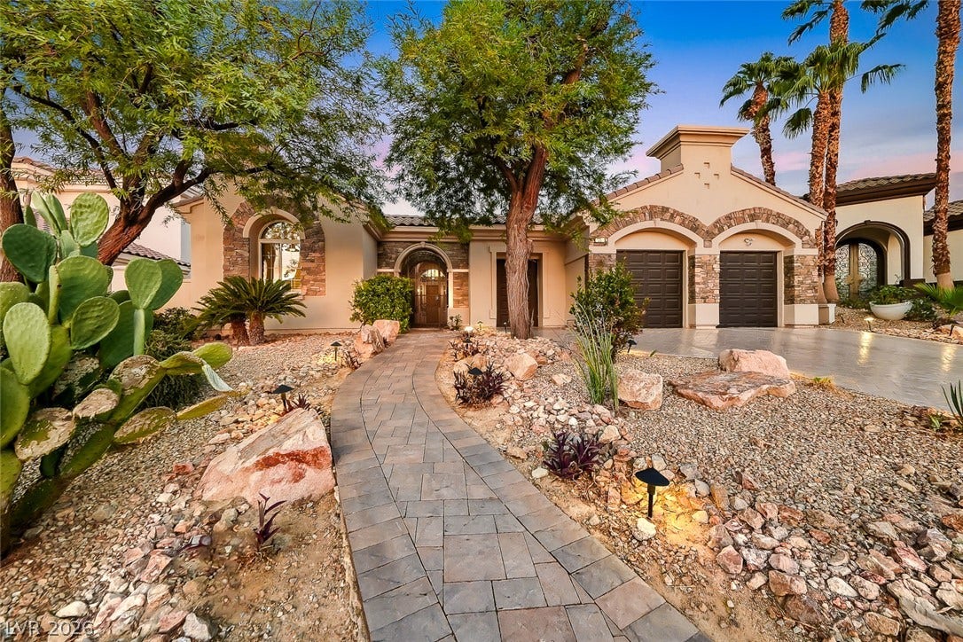 A stone-paved walkway winds through low-maintenance desert landscaping toward the front entryway.