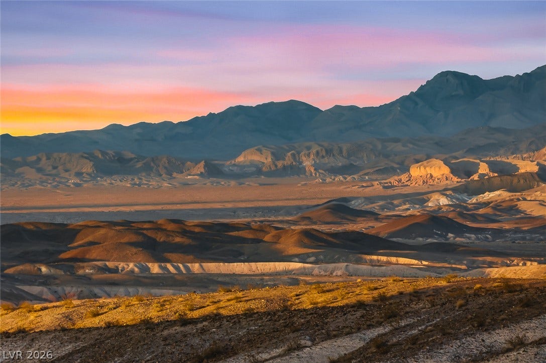 Unobstructed desert and mountain vistas stretch across the horizon under a twilight sky.